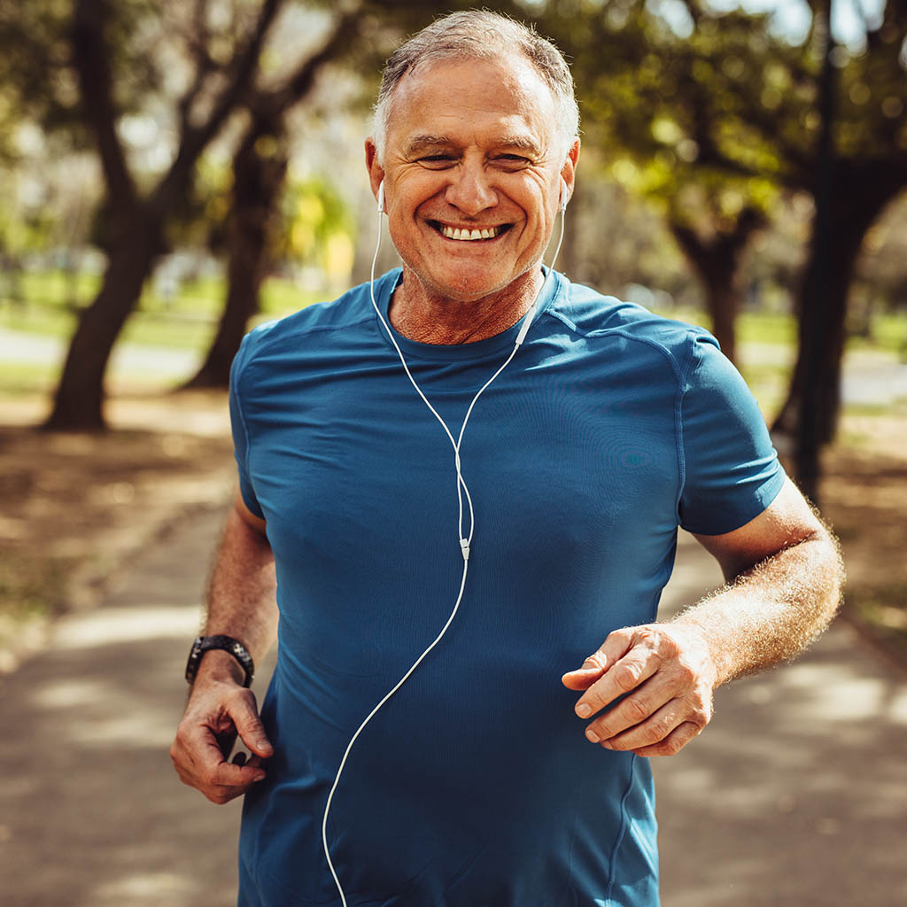 Signore che corre nel parco con le cuffie. L'attività fisica aiuta a prevenire l'Alzheimer