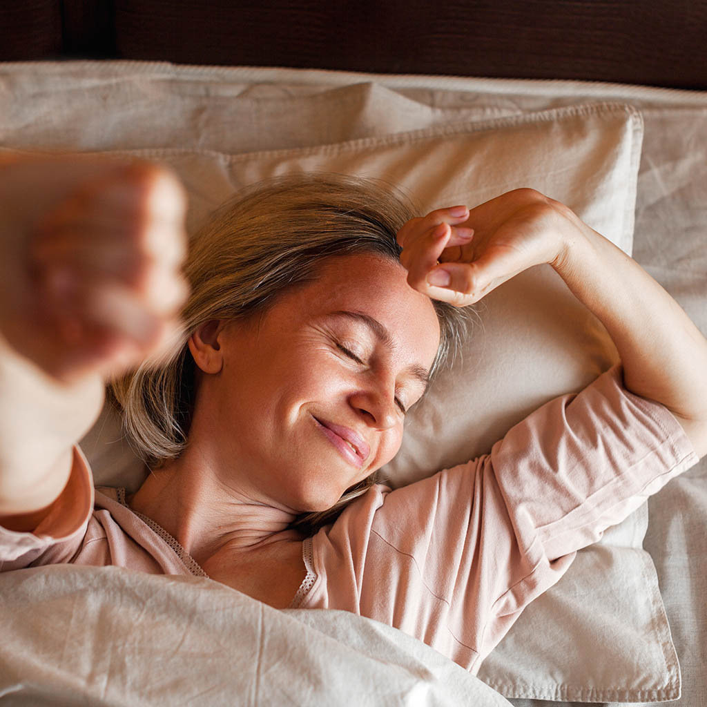 Donna appena sveglia al mattino che si stira. Una buona qualità del sonno aiuta a prevenire l'Alzheimer